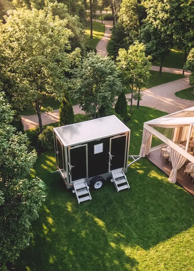 Aerial view of a restroom trailer beside a wedding tent on a green lawn